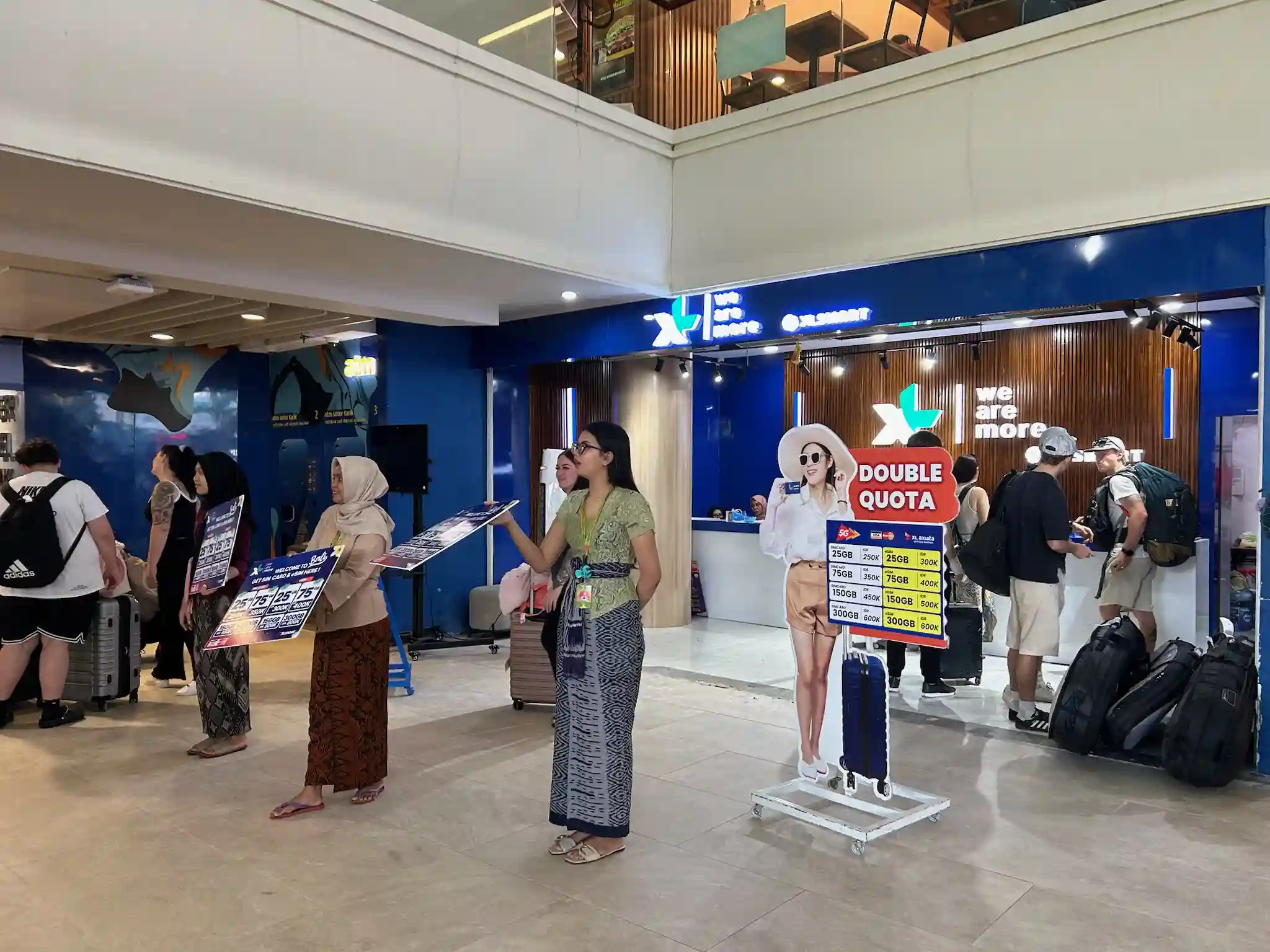 XLSMART airport staff explaining Bali SIM and eSIM packages to a traveller